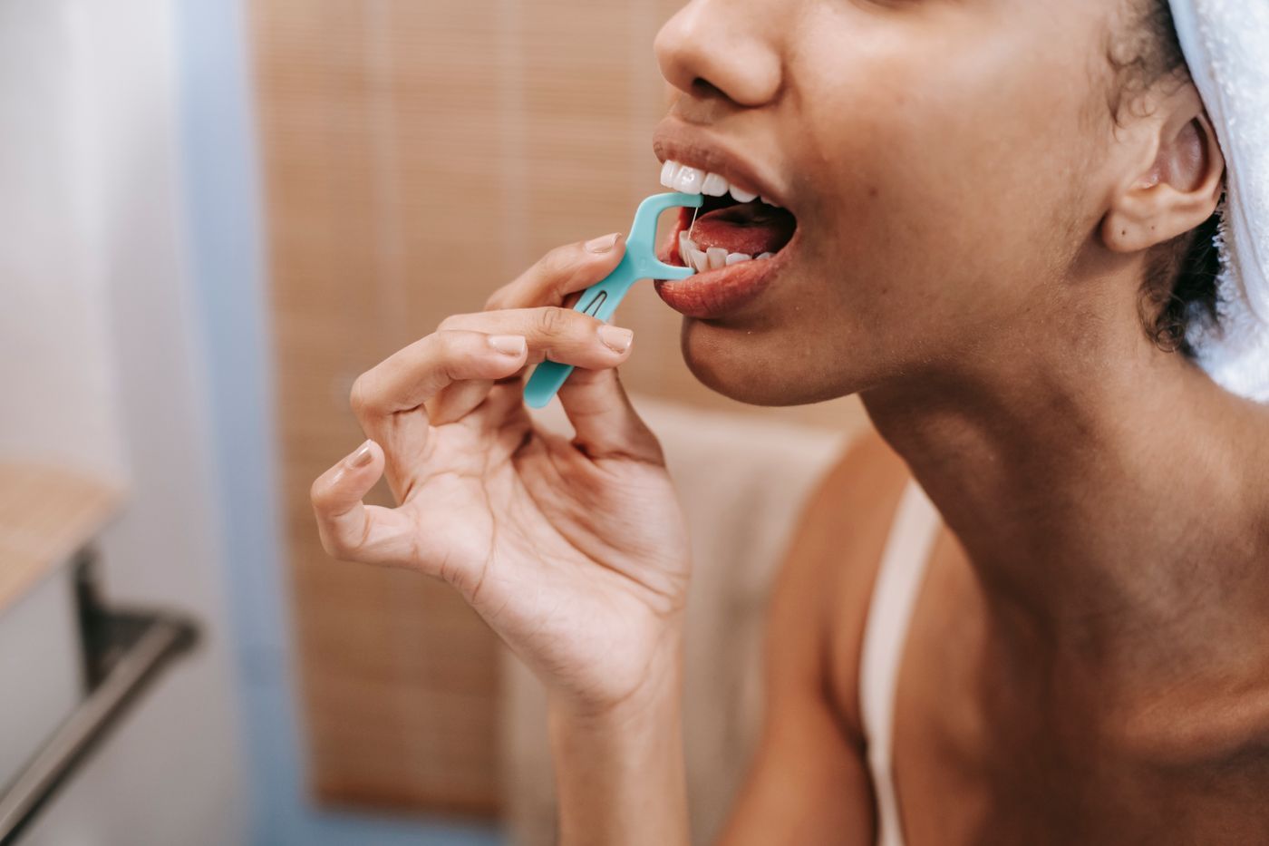 Limpieza entre los dientes con seda dental delante del espejo