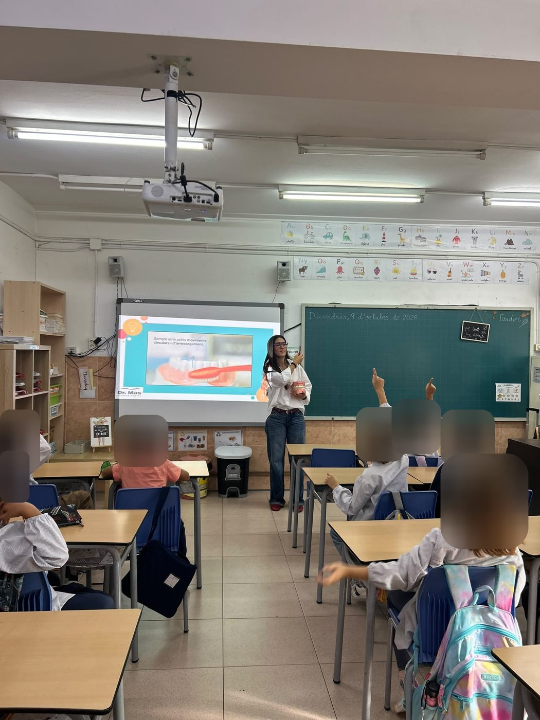 Aula de la Escuela Manent con la presentación de la Clínica Dental Dr. Mas proyectada