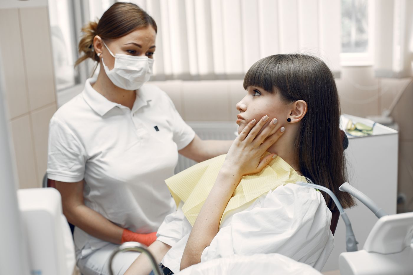 Dentista revisando a una paciente con dolor e hinchazón en la mejilla por un flemón